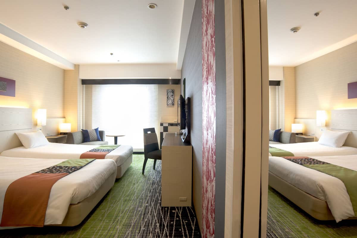 Ein Hotelzimmer mit zwei Betten, einem Schreibtisch und einem Stuhl.