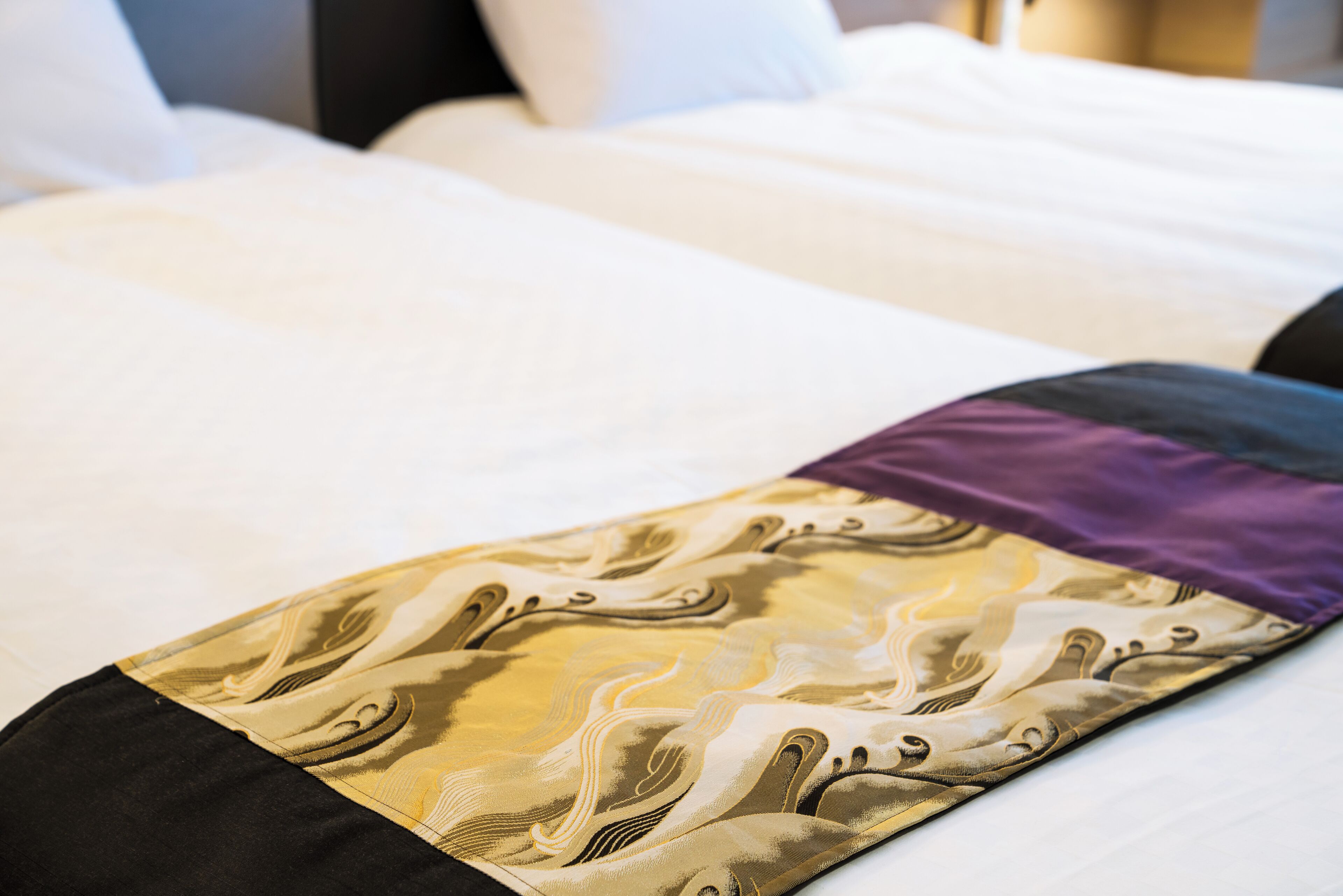 A bed with a patterned bedspread and a pillow.