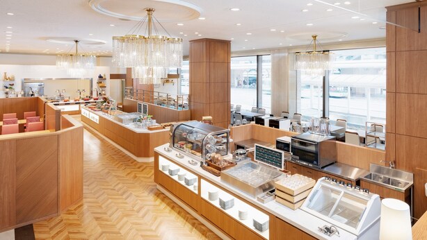 Una cafetería moderna con muebles de madera, una barra central con una máquina de café y un candelabro.