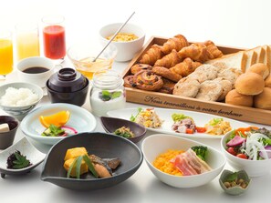 Variedad de opciones para el desayuno, incluyendo cruasanes, pasteles y una selección de frutas y verduras.