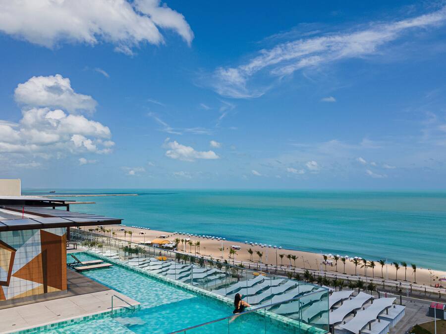 Ein Resort mit Schwimmbad, Blick auf den Strand und Palmen.