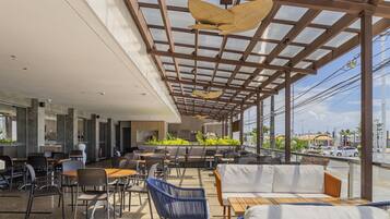 An outdoor seating area with tables and chairs, a wooden bench, and a sofa.