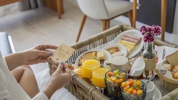 Bandeja de café da manhã com suco de laranja, frutas, doces e um cartão.