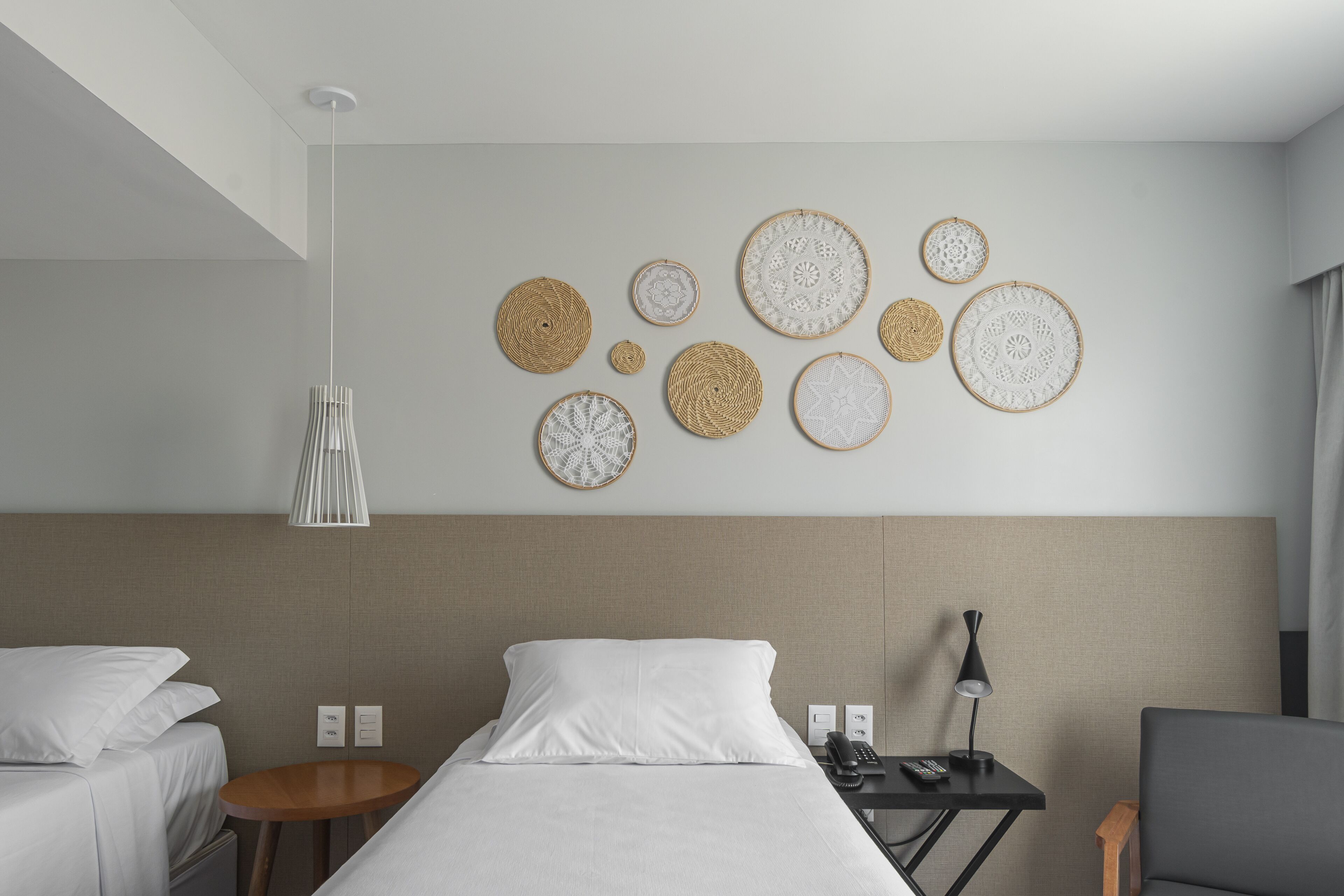 Une chambre d’hôtel comprenant un lit, des tables de chevet, une lampe et des œuvres d’art décoratives au mur.