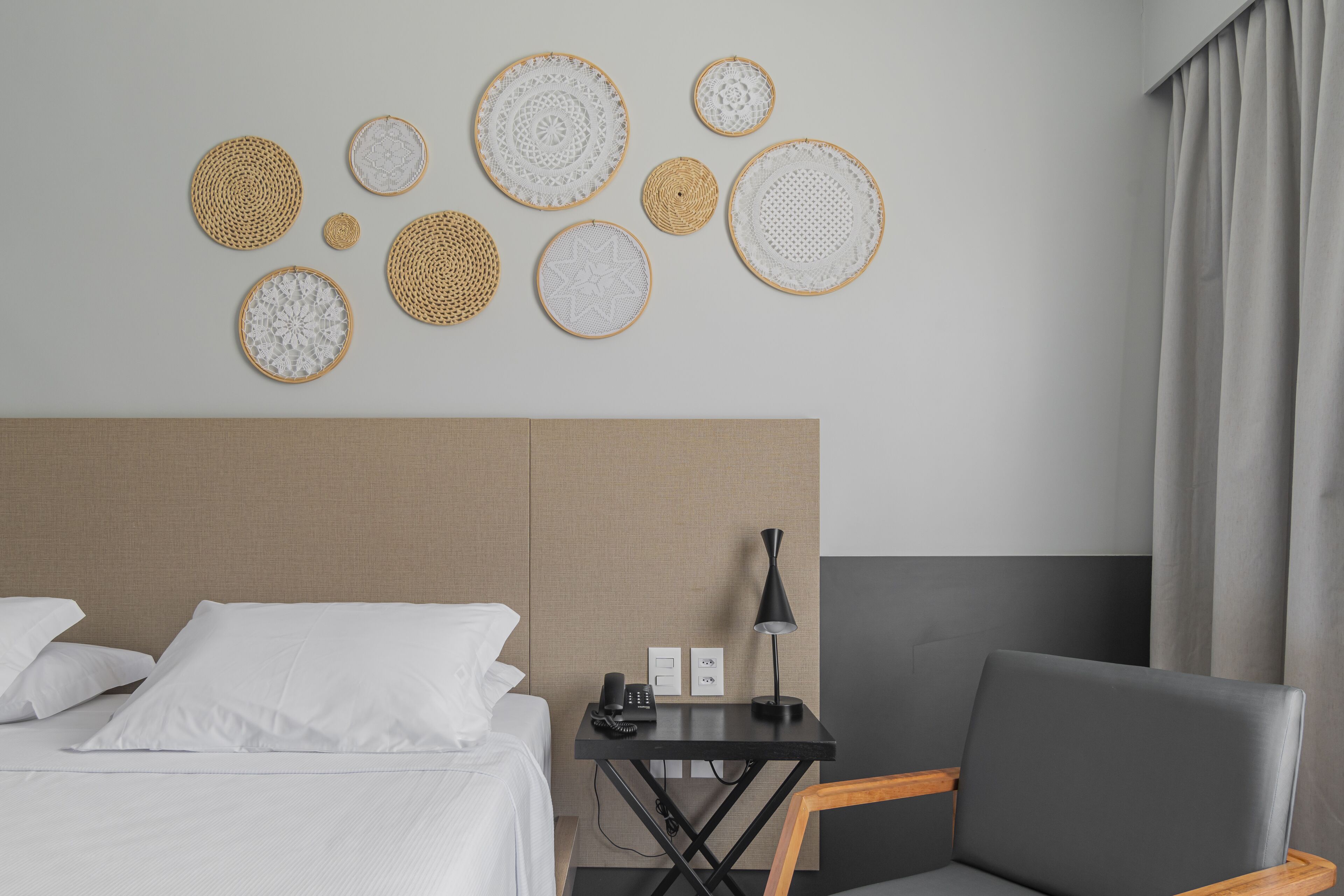 A hotel room with a bed, a desk, a chair, and wall decor.