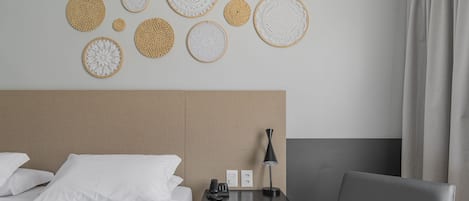 A hotel room with a bed, a desk, a chair, and wall decor.