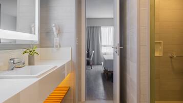 A modern bathroom with a large mirror, a sink, and a shower area.