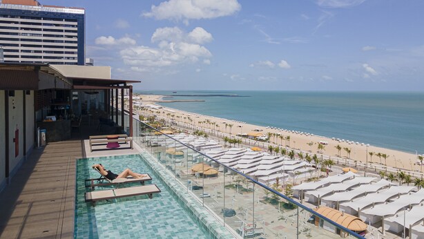 Área da piscina com vista para a praia e oceano.