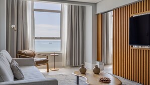 Uma sala de estar moderna com um sofá, poltrona, mesa de centro e uma televisão.