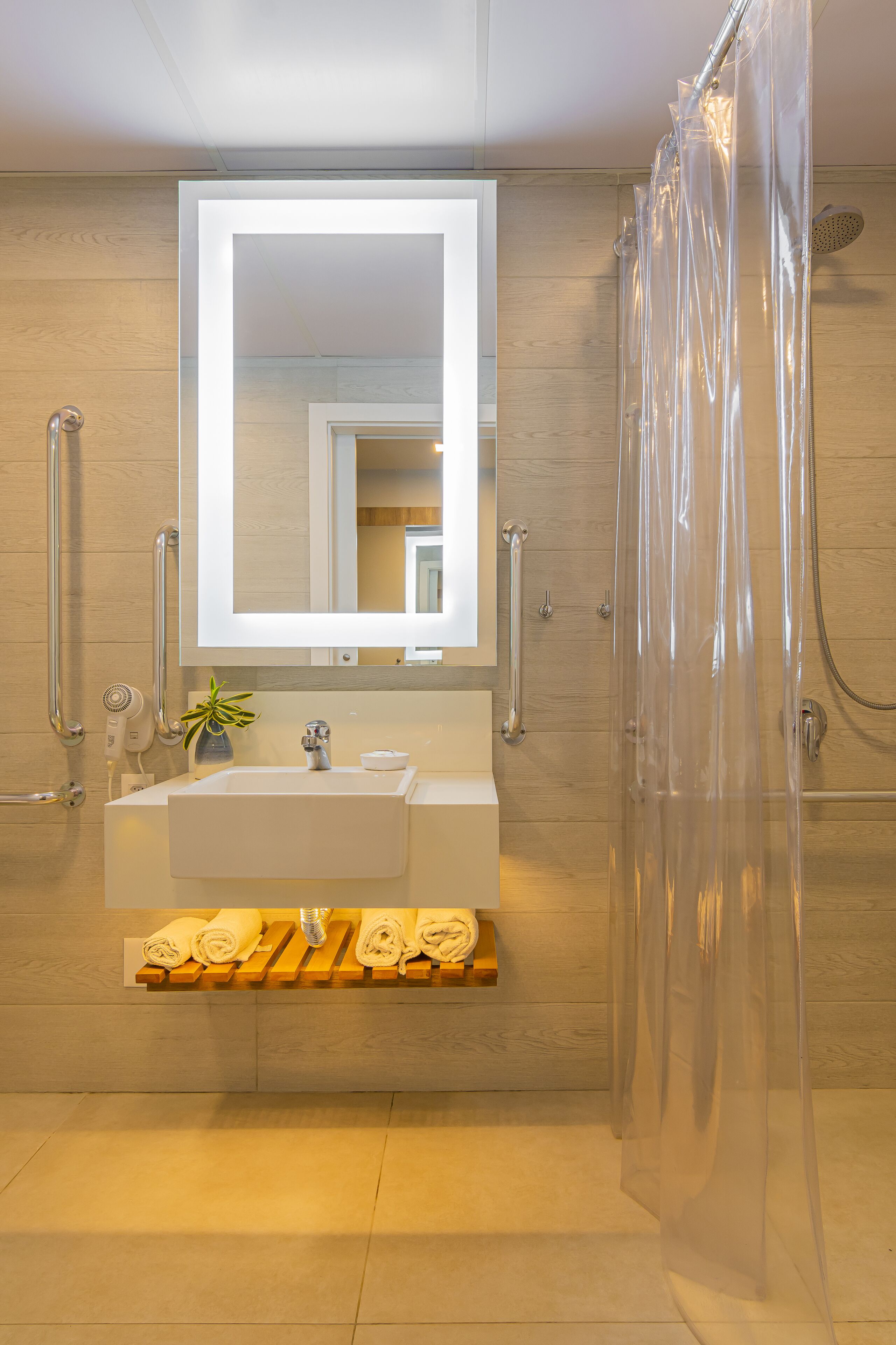 Un baño moderno con un espejo grande, un lavamanos y una cabina de ducha.