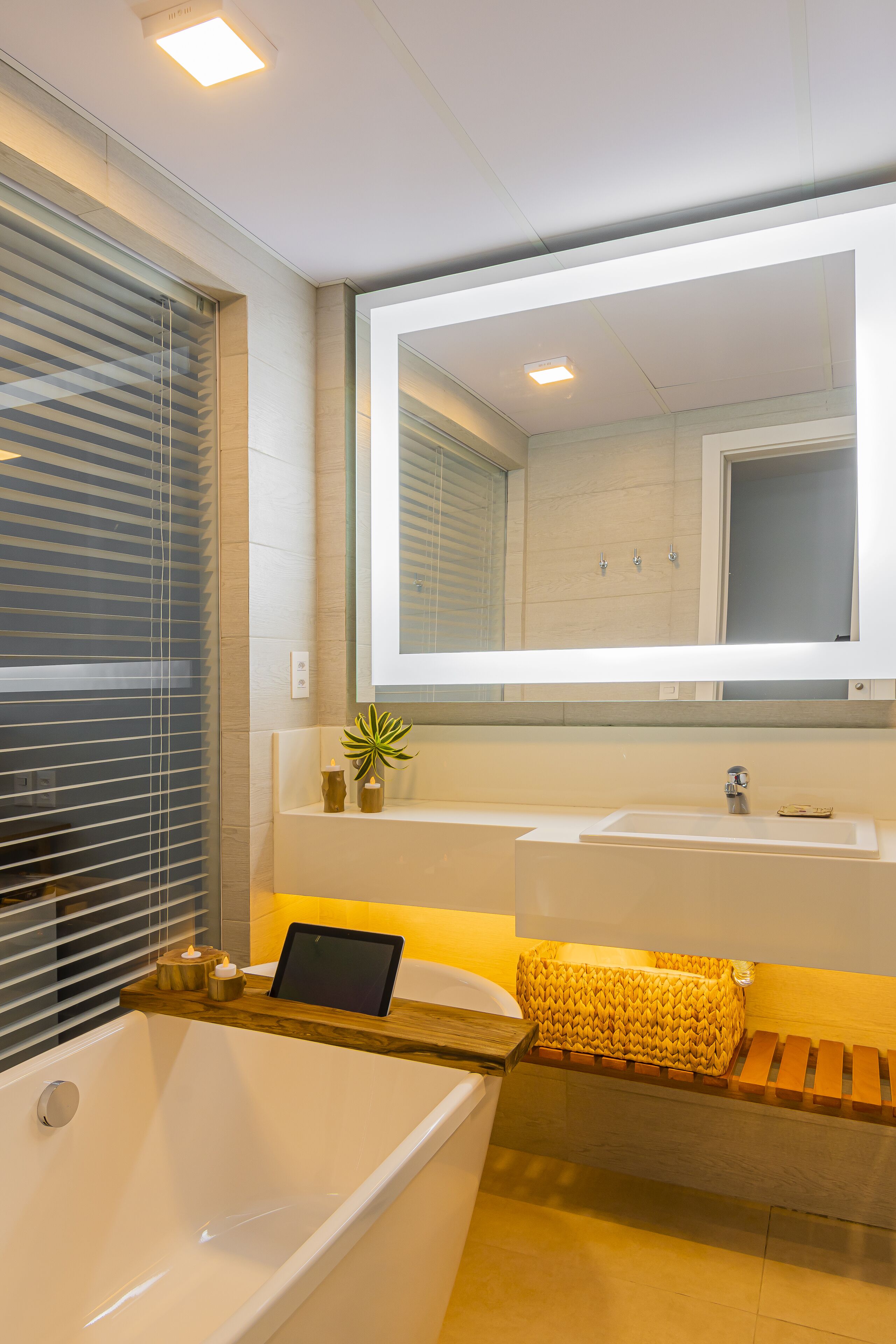 A modern bathroom with a bathtub, a large mirror, and a wooden vanity.