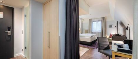 Una habitación de hotel con cama, escritorio, silla, armario y puerta.