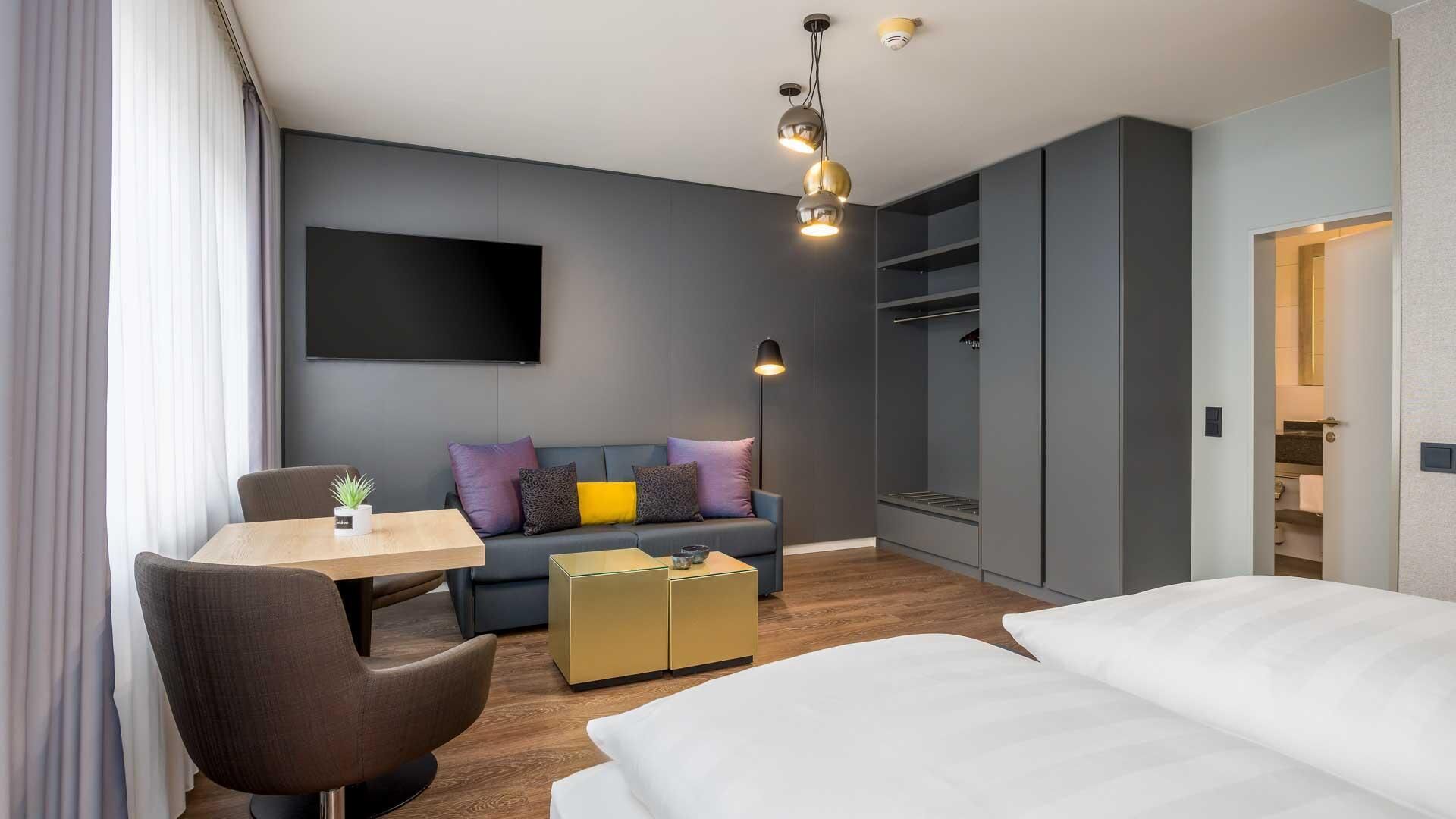 Een moderne hotelkamer met een bed, een bank, een bureau en een kledingkast.