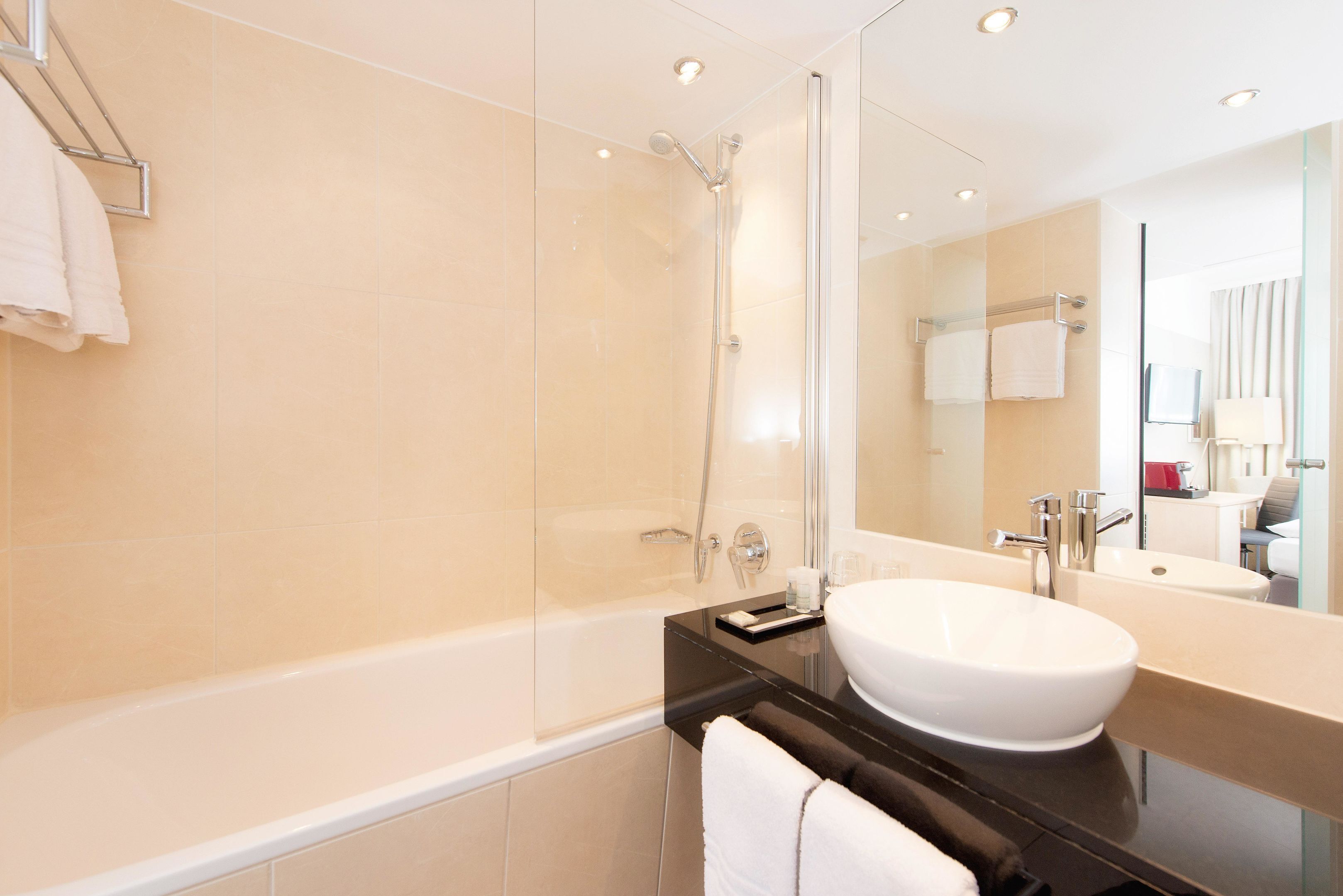 A modern bathroom with a glass-enclosed shower, a white sink, and a large mirror.