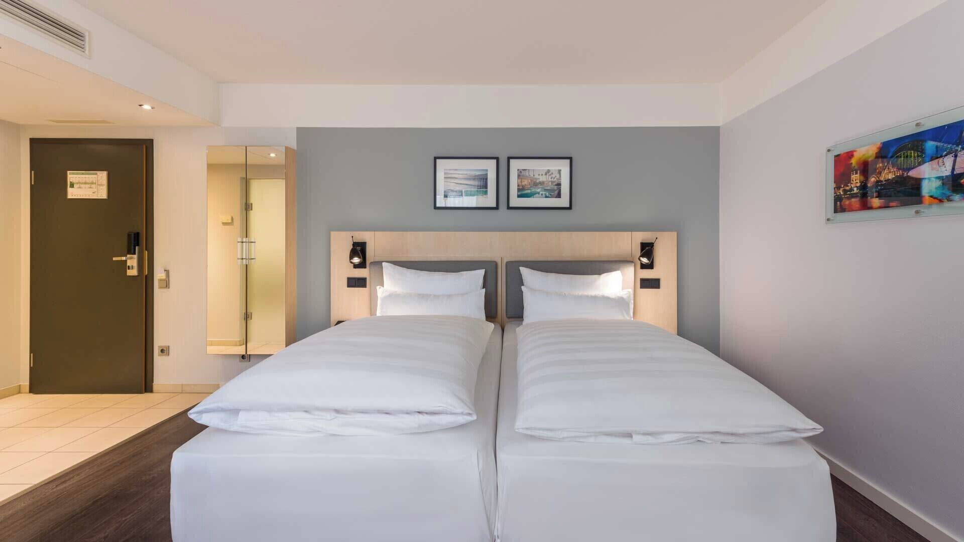 A double bed with a wooden headboard, a nightstand, and a wall-mounted lamp.