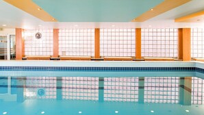 A swimming pool with tiled walls and benches along the side.