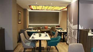 Un comedor moderno con mesas y sillas, un techo estampado y un diseño de pared con vista a la ciudad.