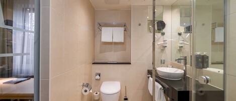 A modern bathroom with a toilet, sink, and glass shower enclosure.