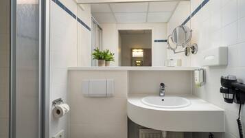 Un baño moderno con un lavabo blanco, un espejo, un secador de pelo y un inodoro.