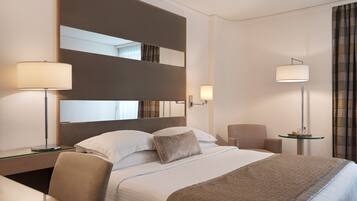 A hotel room with a large bed, two bedside tables, a chair, and a desk with a lamp.
