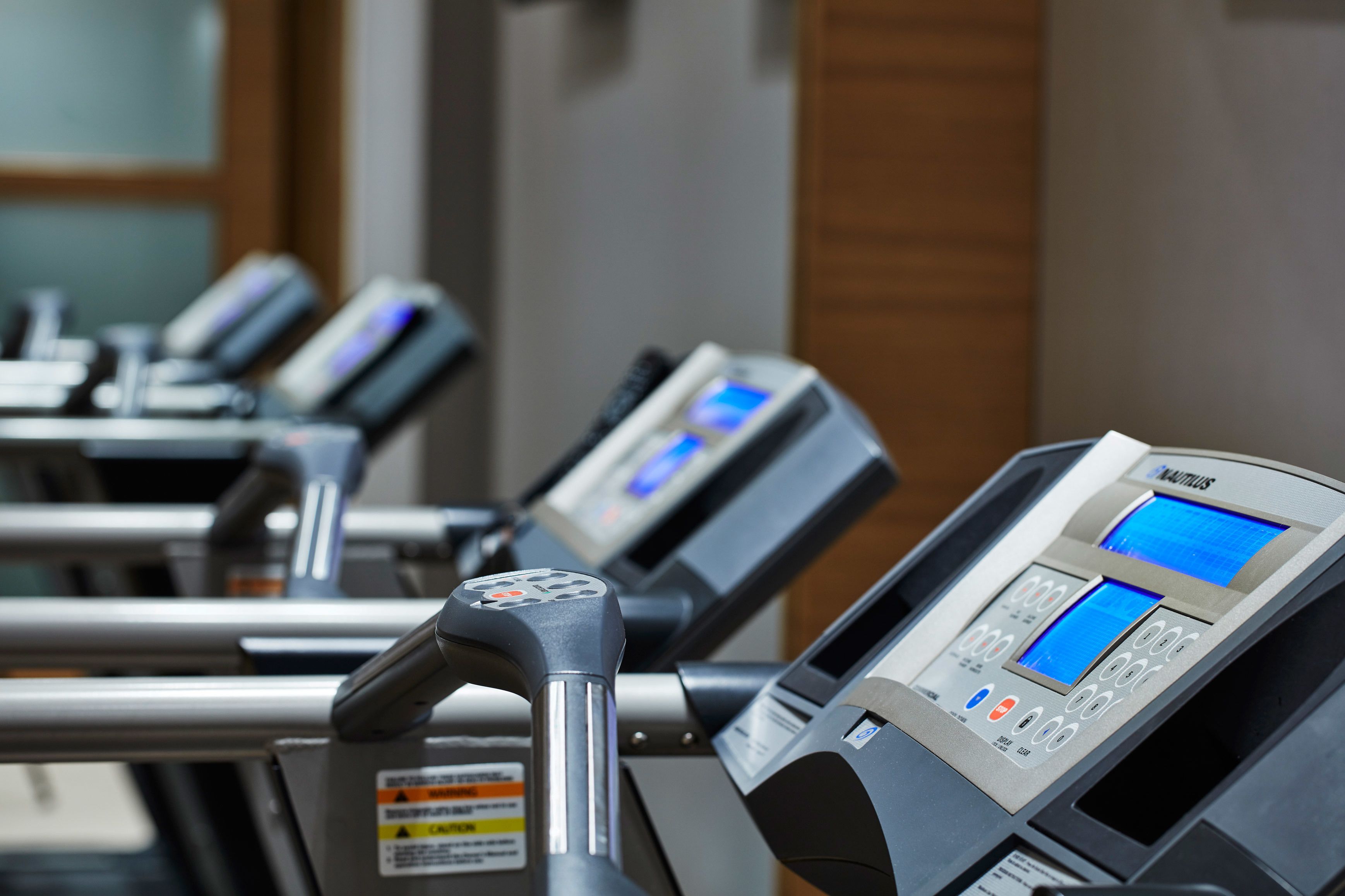 A row of stationary exercise bikes with digital displays and control panels.