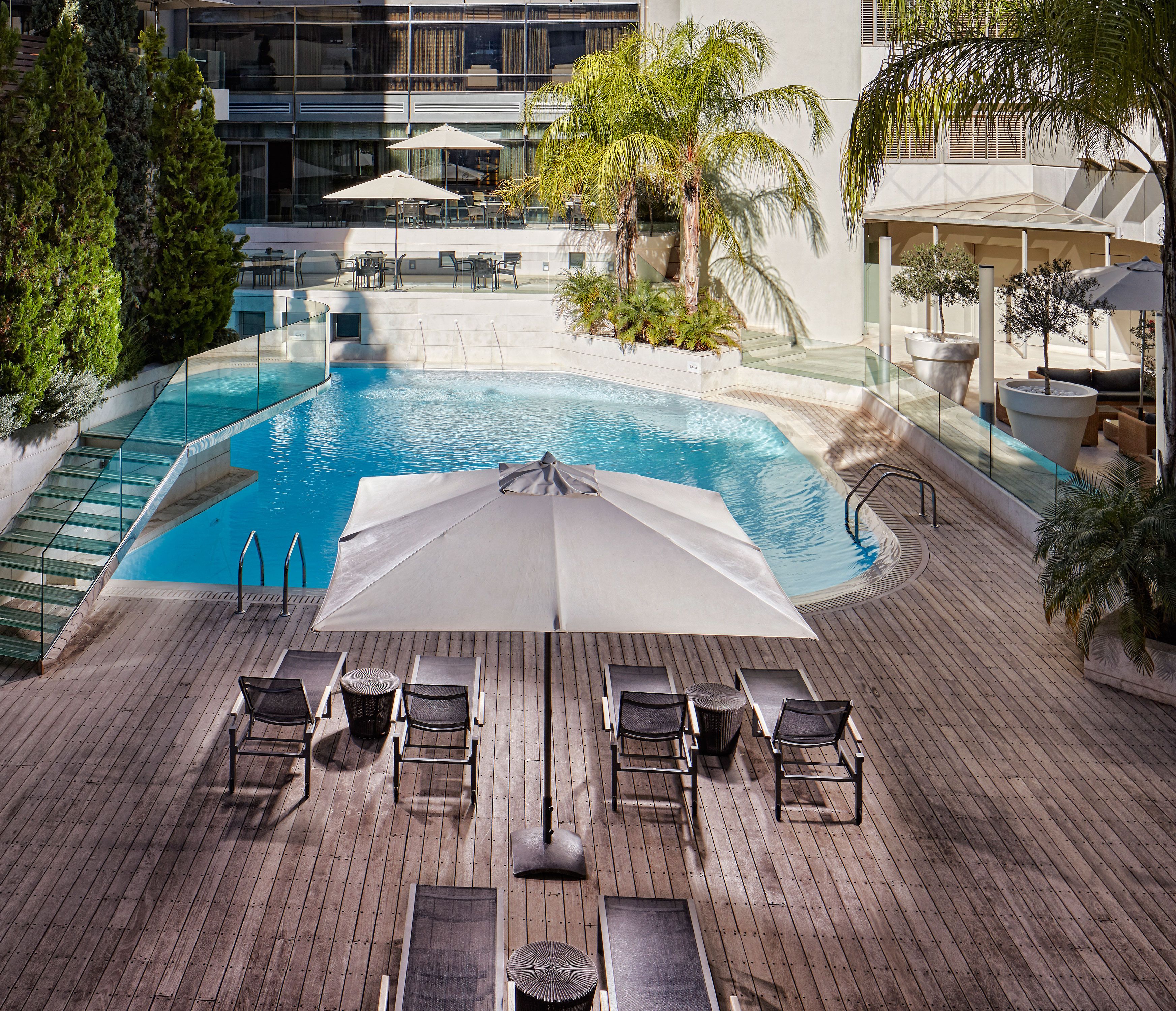A rooftop pool area with lounge chairs, umbrellas, and a clear view of the pool.