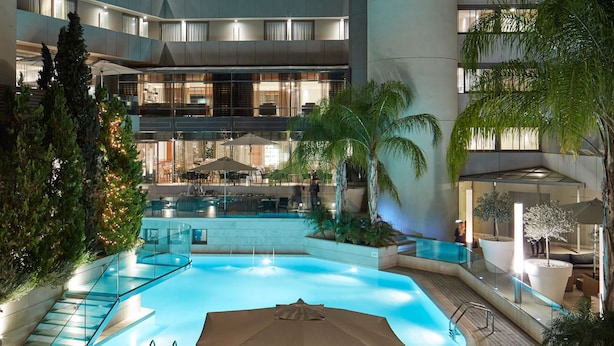 A modern hotel with a central swimming pool, multiple balconies, and outdoor seating areas. - Galaxy Hotel Iraklio (Heraklion)