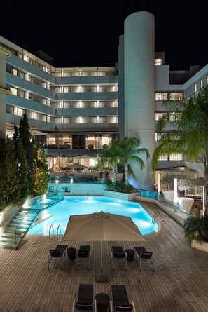 A modern hotel with a central swimming pool, multiple balconies, and outdoor seating areas. - Galaxy Hotel Iraklio (Heraklion)