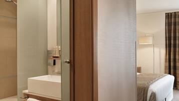 A modern bathroom with a glass shower enclosure, a bathtub, and a vanity with toiletries.
