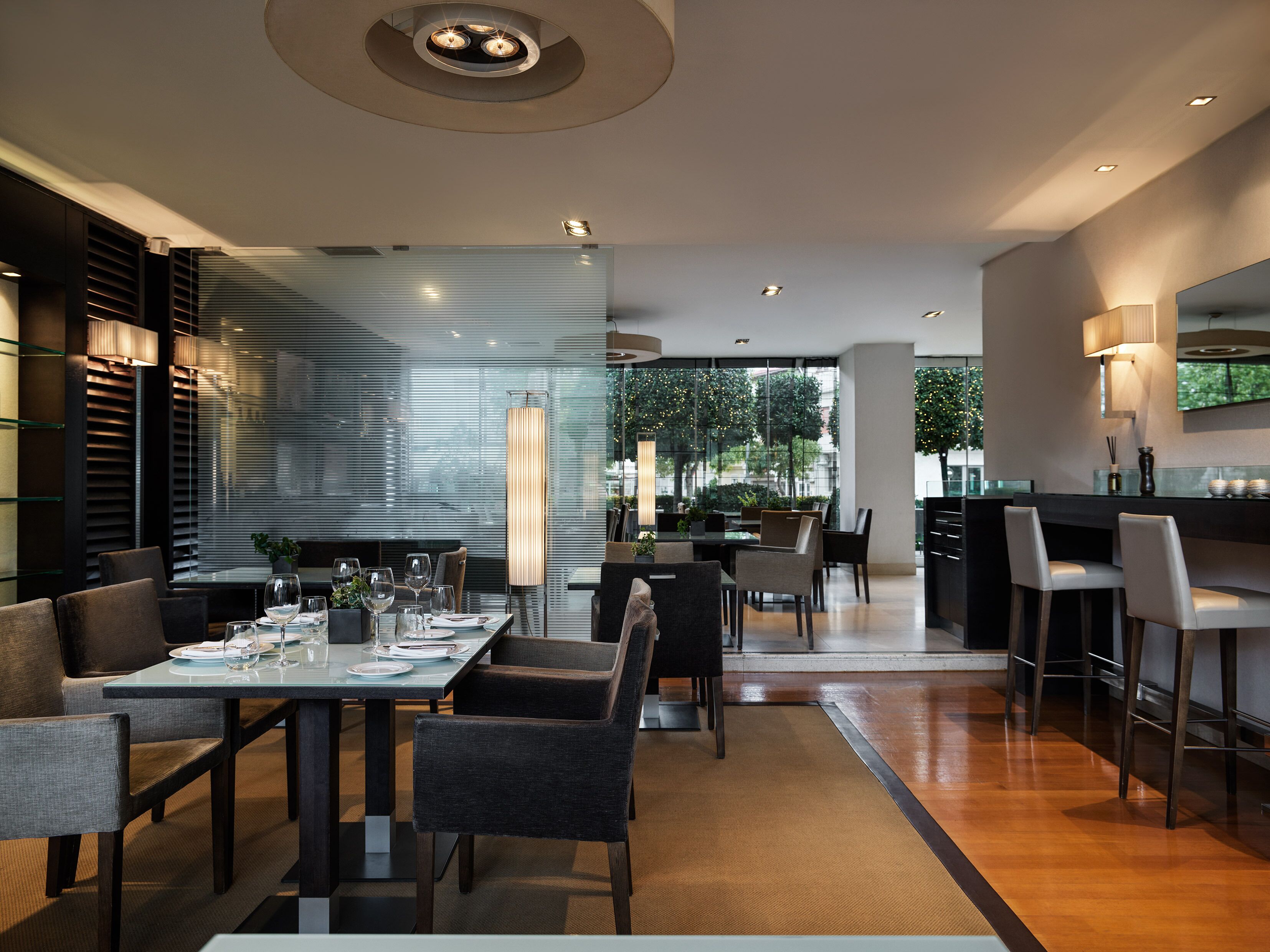 Un comedor moderno con una mesa larga, sillas y una zona de bar con taburetes.