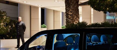 A Galaxy Hotel entrance with a modern design, a palm tree, and a car interior visible through the window.