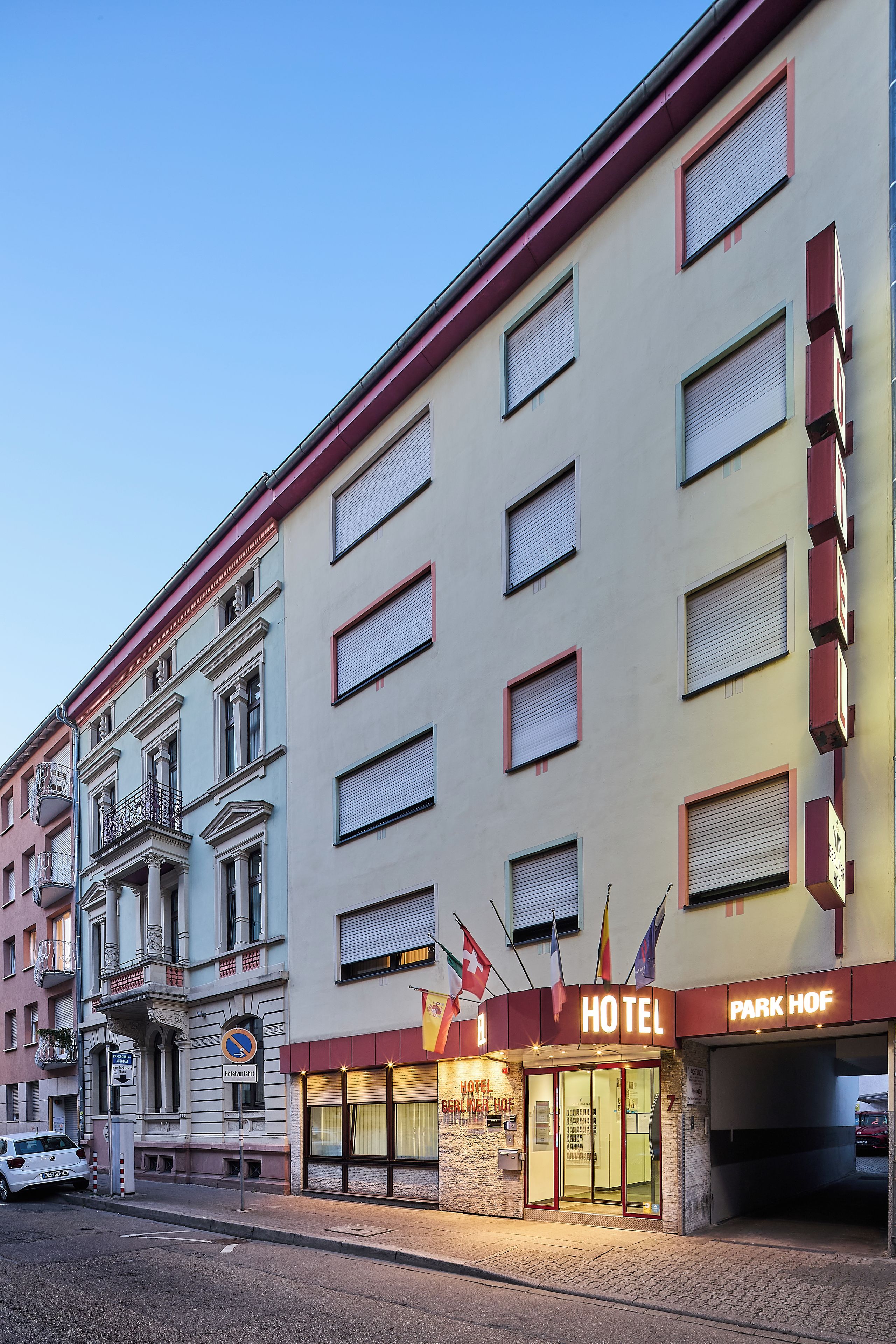 Un hotel con fachada clásica, numerosas ventanas y un letrero llamativo que indica su nombre.