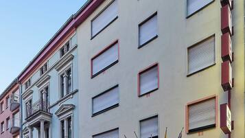 Un hotel con fachada clásica, numerosas ventanas y un letrero llamativo que indica su nombre.