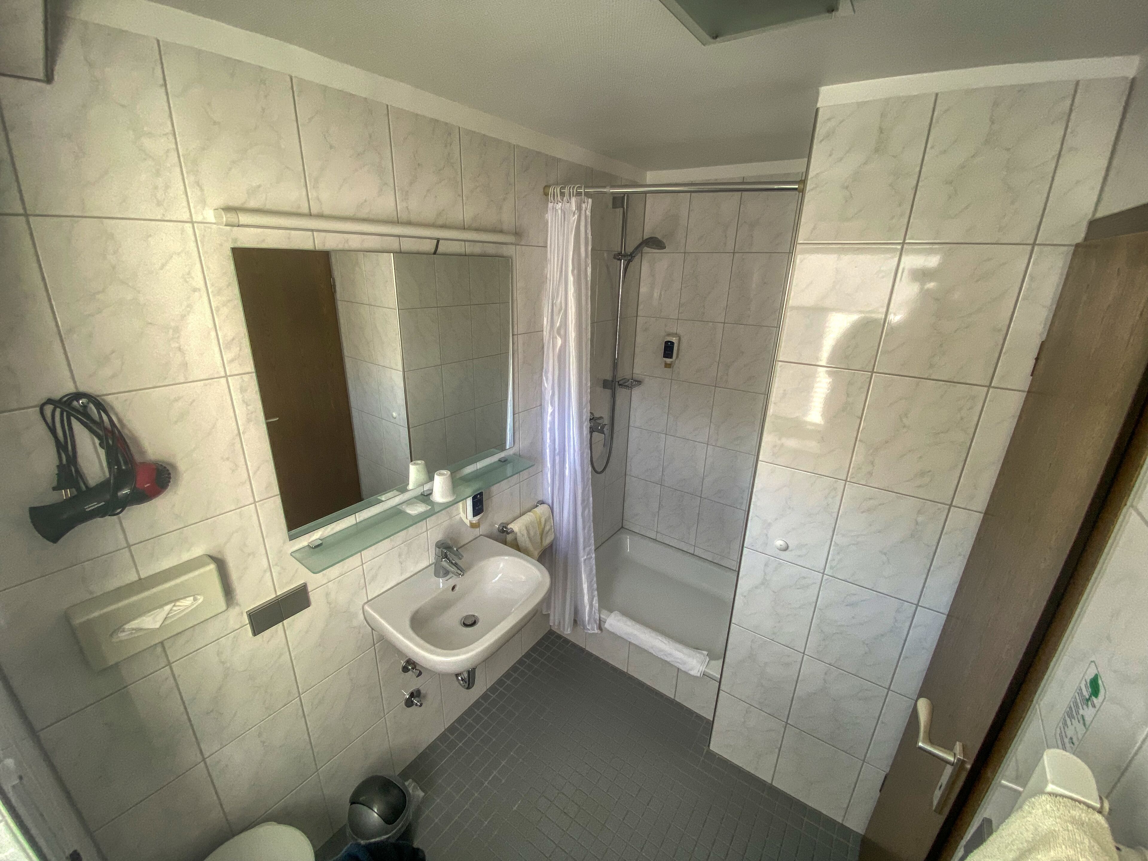 Ein Badezimmer mit Dusche, Waschbecken und Spiegel.