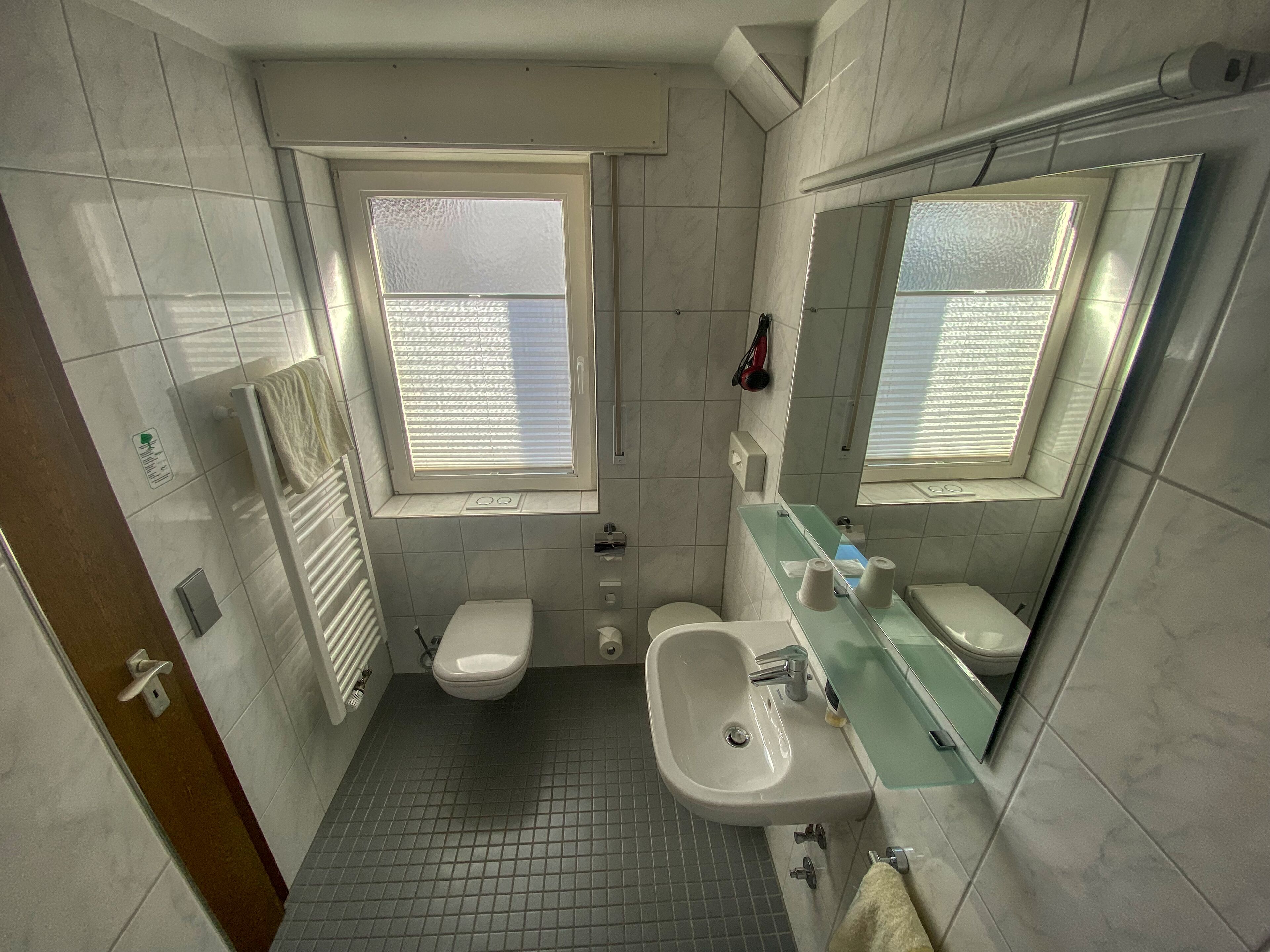 A bathroom with a toilet, sink, and a window.