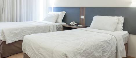 Camera d'albergo con due letti, un comodino e un telefono.