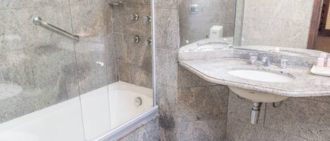 Une salle de bain moderne avec une douche à parois de verre, un lavabo sur un plan de travail en granit et un miroir.