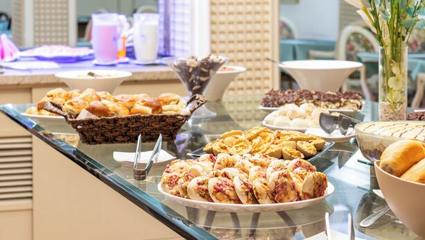 Ein Buffet mit verschiedenen Speisen, darunter Gebäck, Desserts und einer Blumenkomposition.