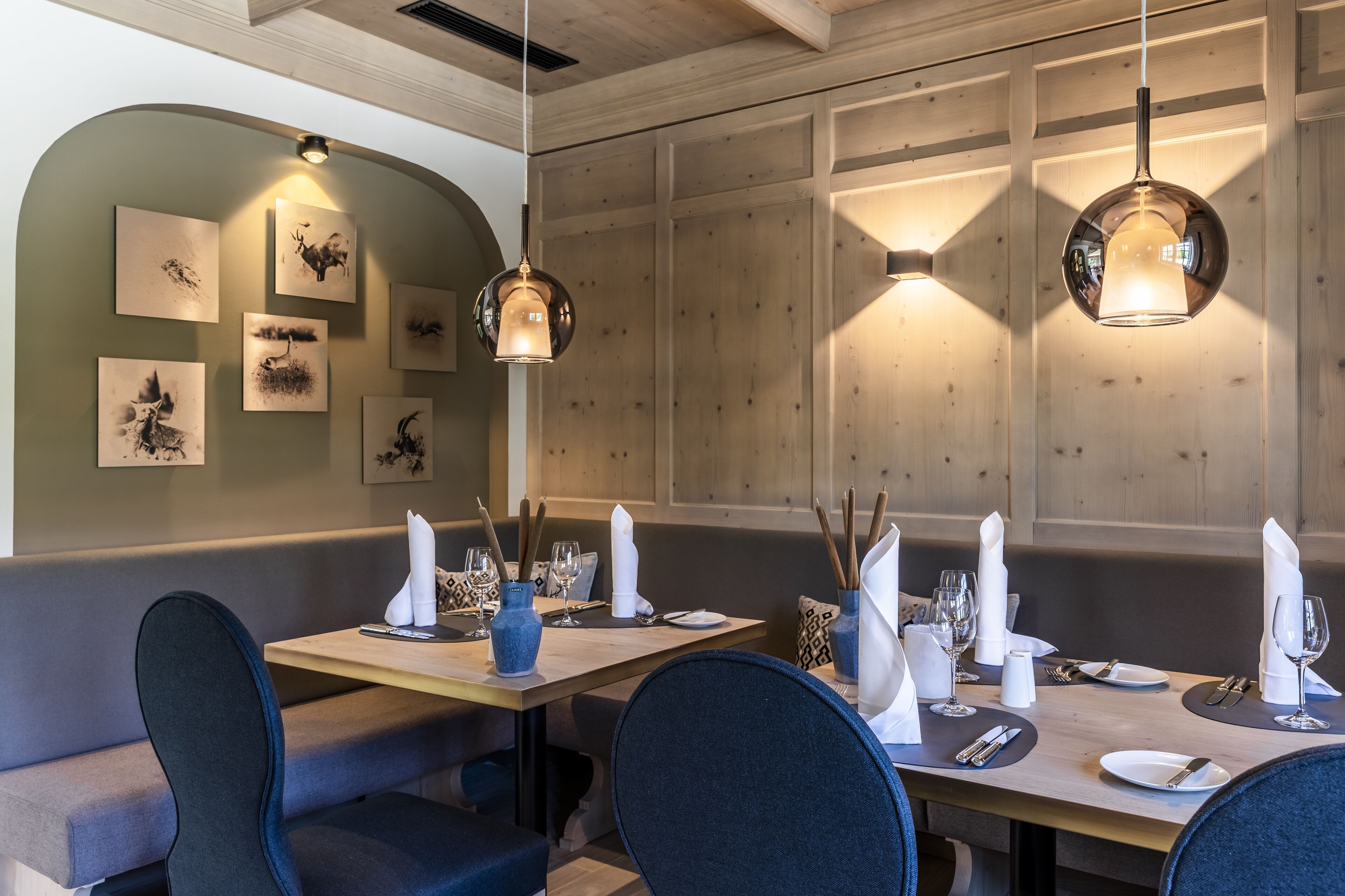 A restaurant with wooden panel walls, round pendant lights, and artwork on the wall.