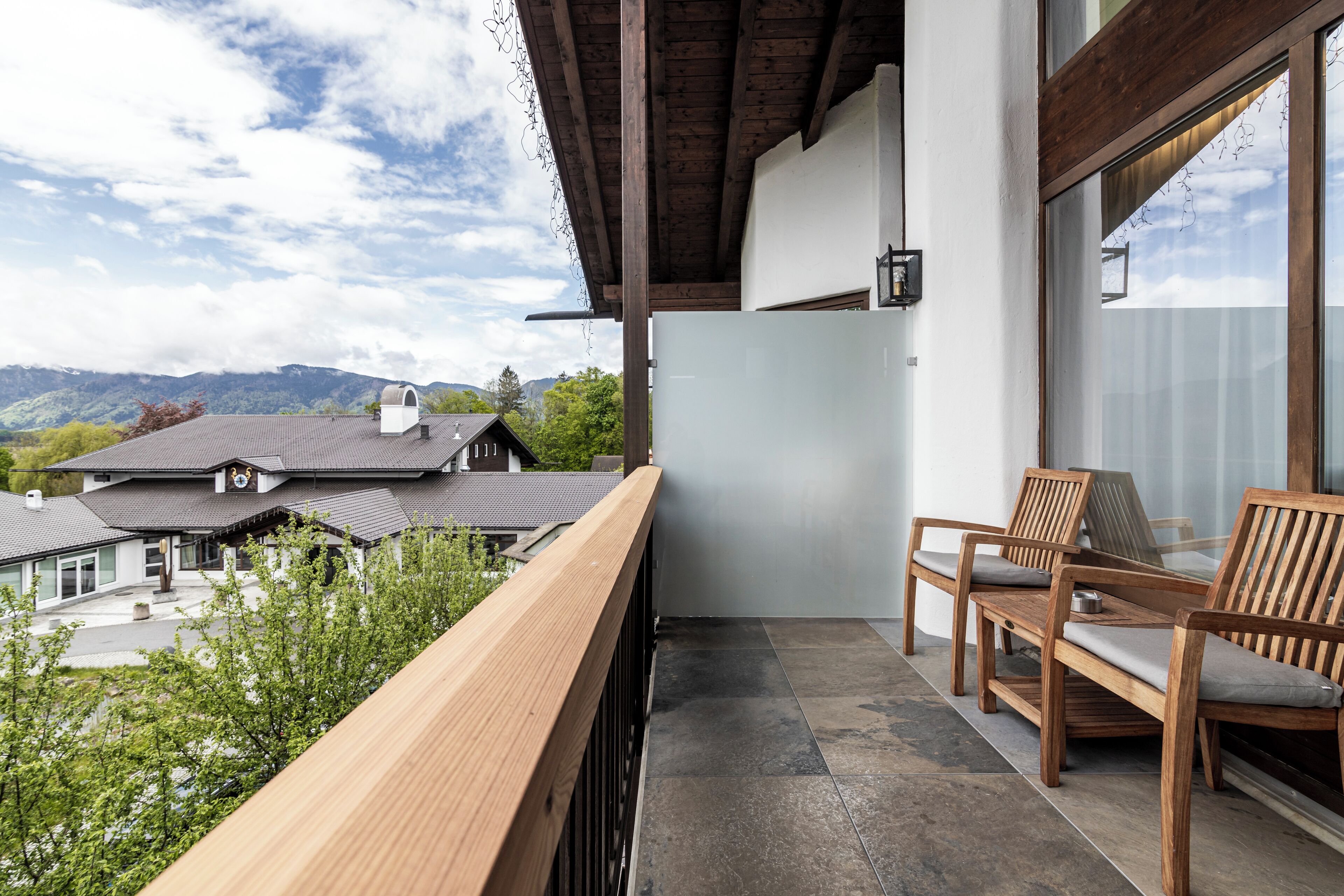 Ein Balkon mit Holzbalkonen, einer Glastür und zwei Holzstühlen.