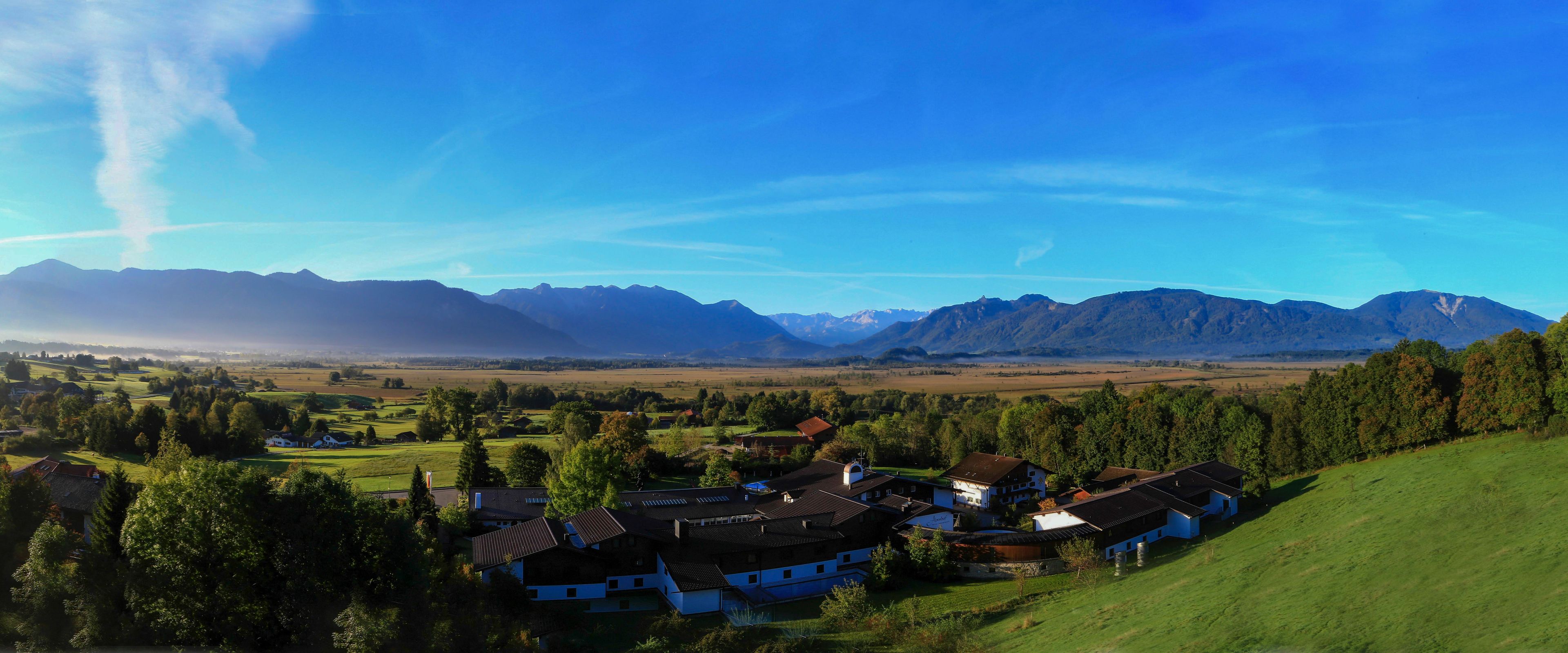 Un pueblo rural con casas tradicionales, una iglesia y vistas a montañas distantes.