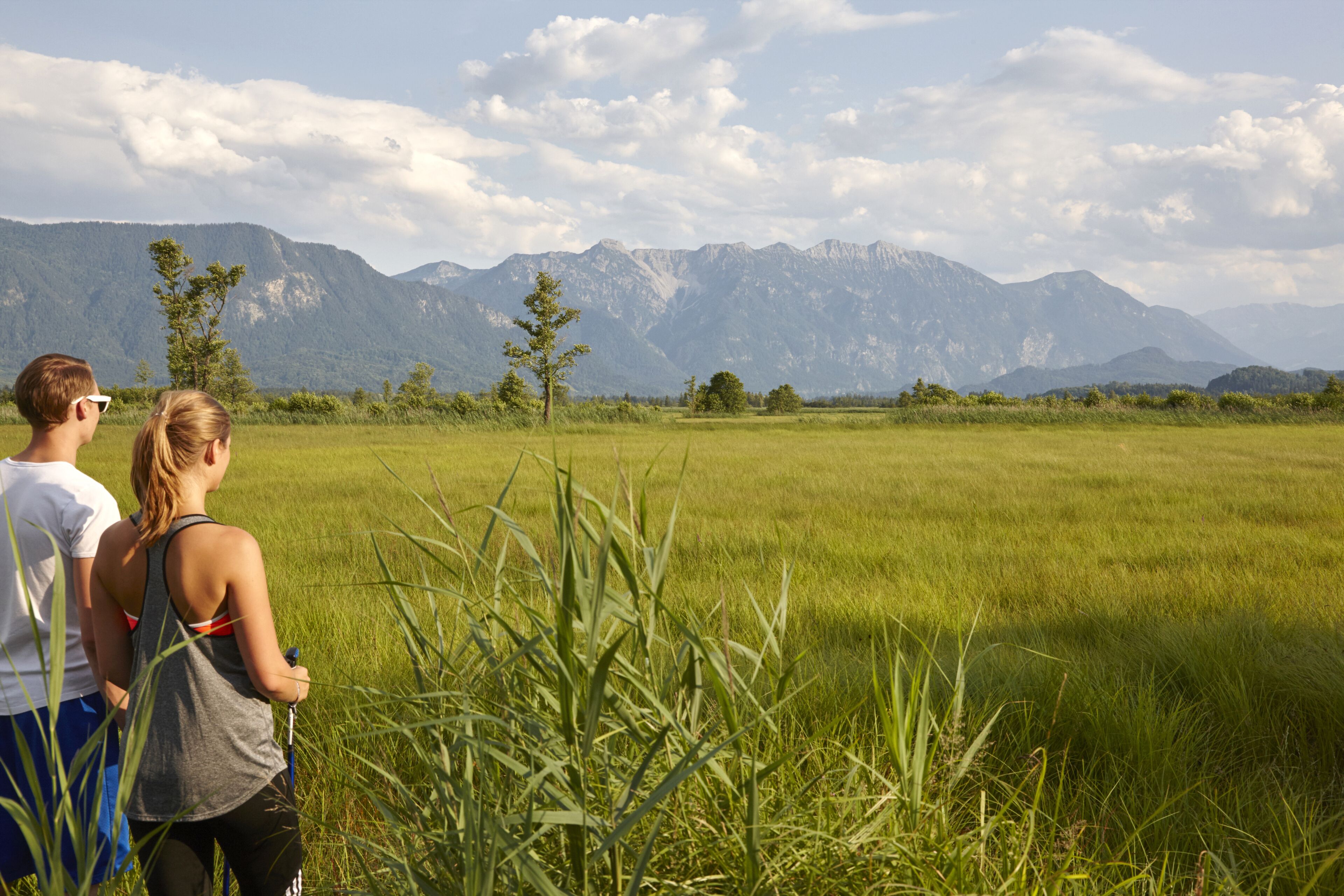 A couple standing in a field with mountains in the background.