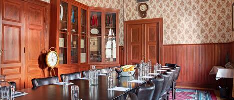 A conference room with a long table, chairs, a clock, and a cabinet with glass doors.