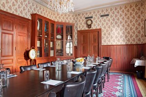 A conference room with a long table, chairs, a clock, and a cabinet with glass doors.