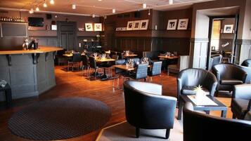A modern restaurant with a bar area, multiple seating options including booths and tables, and a variety of framed pictures on the walls.
