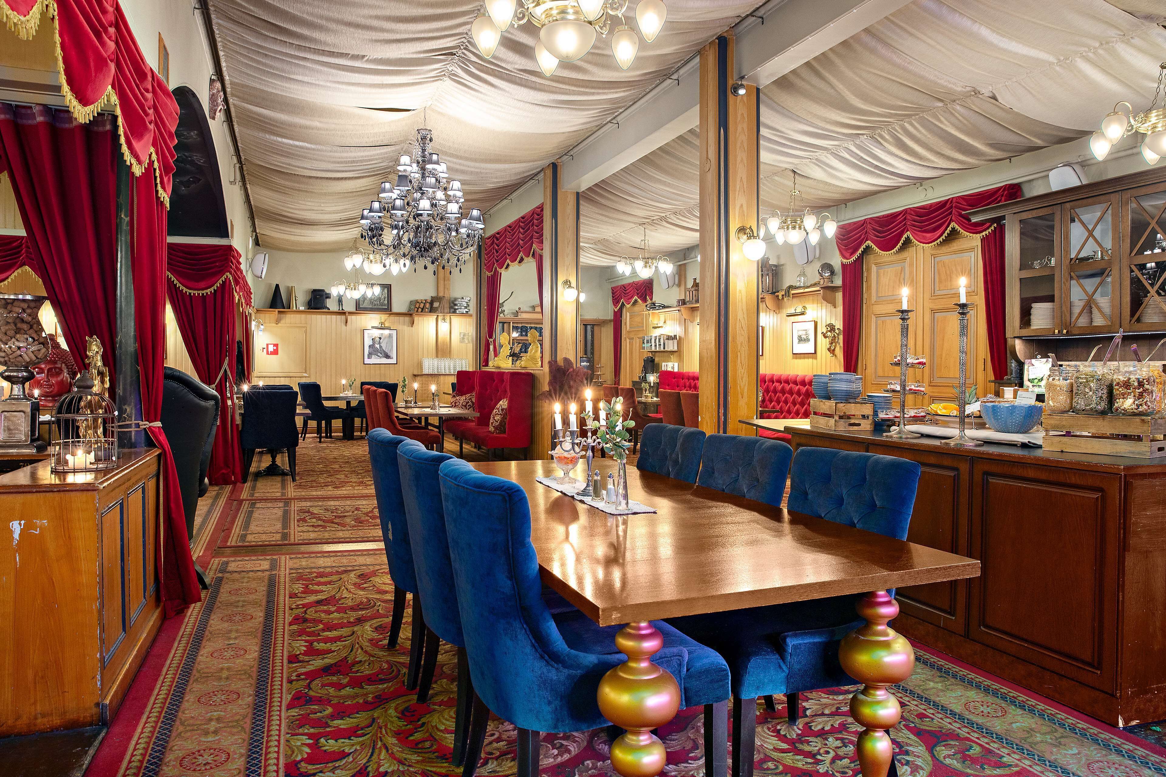 Un comedor formal con una mesa de madera, sillas tapizadas en azul y una araña.