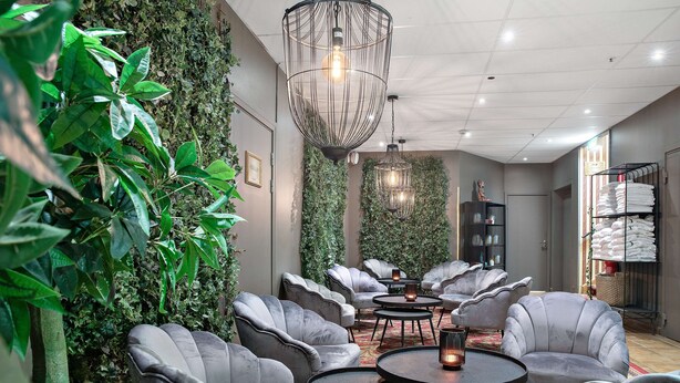 A modern lounge area with grey upholstered chairs, round tables, and a green wall with climbing plants. - Best Western Hotel Gamla Teatern (Östersund)