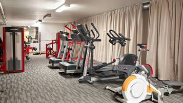 A gym with various exercise equipment including treadmills, ellipticals, and a weight machine.