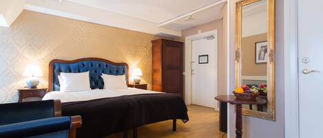 A hotel room with a bed, bedside tables, a mirror, and a wooden wardrobe.