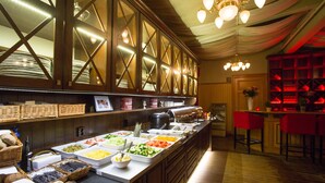 A buffet area with various food items, a counter with a coffee machine, and a bar area with red chairs. - Best Western Hotel Gamla Teatern (Östersund)